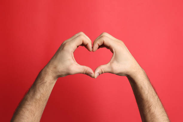 istock Man making heart with his hands on red background, closeup 1452867206