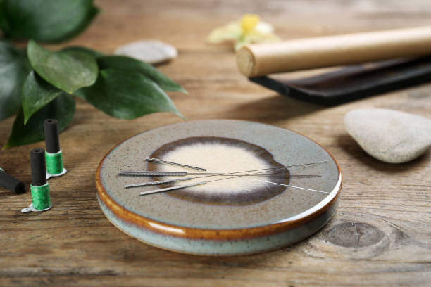 istock Grey stone coaster with acupuncture needles on wooden table 1452867241