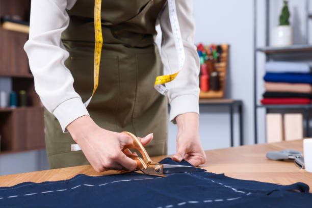 istock Dressmaker cutting fabric by following chalked sewing pattern in workshop, closeup 1452867243