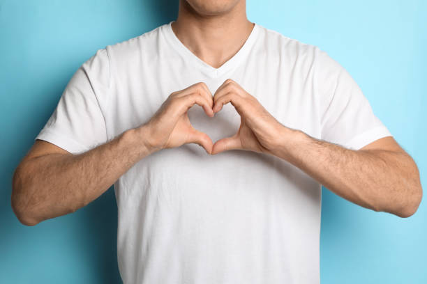 istock Man making heart with hands on light blue background, closeup 1452867445