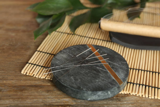 istock Grey stone coaster with acupuncture needles on wooden table 1452867521