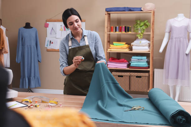 istock Dressmaker working with light blue fabric in atelier 1452868017