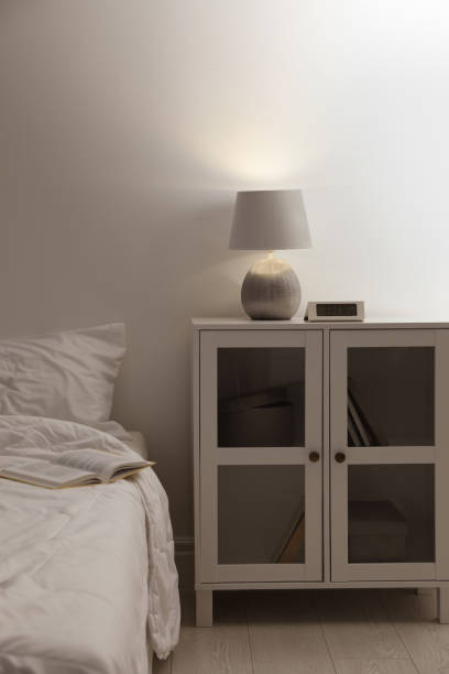 istock Stylish lamp and alarm clock on bedside table indoors. Bedroom interior elements 1452868991