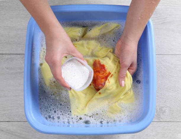 istock Woman adding powdered detergent into basin with clothes, top view. Hand washing laundry 1452870561