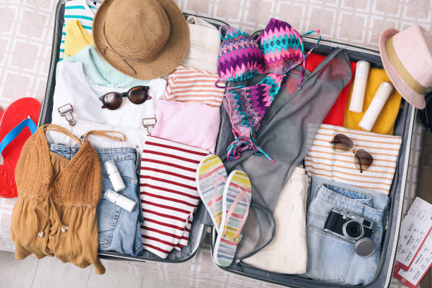 istock Open suitcase with summer clothes, accessories and shoes on bed, flat lay 1452870884