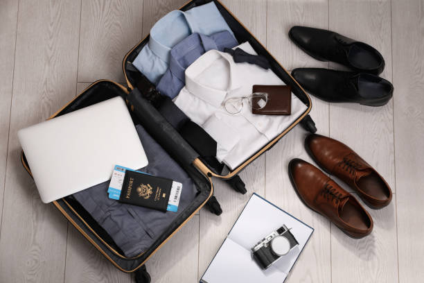 istock Open suitcase with men's clothes, accessories and shoes on floor, flat lay 1452871433