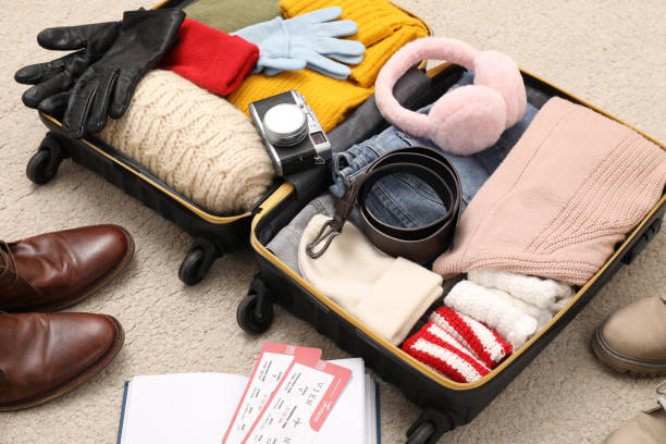 istock Open suitcase with warm clothes, accessories and shoes on floor 1452871501
