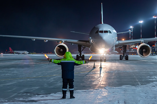 Airliner marshalling at the aiport apron at winter night