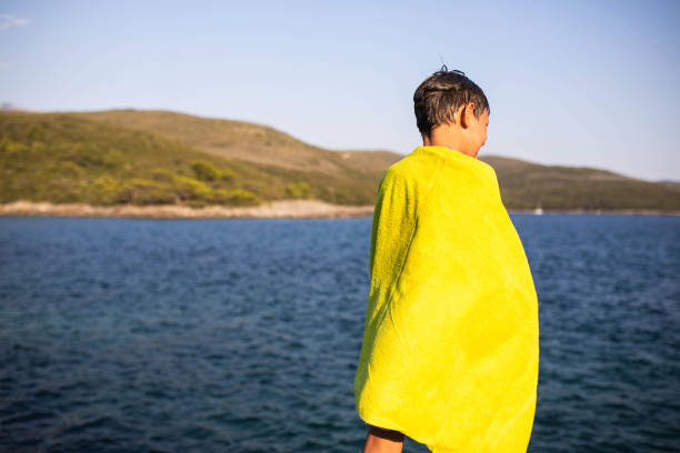A wet boy wrapped in a towel at the beach stock photo
