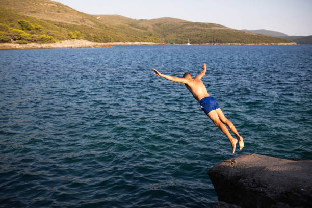 istock A young man jumping off a cliff into the sea 1452871746