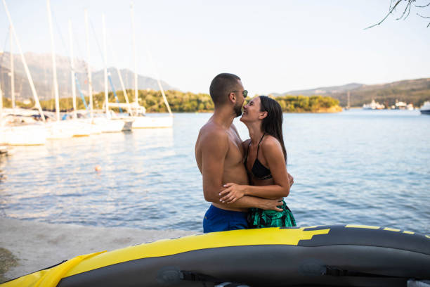 An attractive happy couple is carrying their kayak to the water at a beach resort
