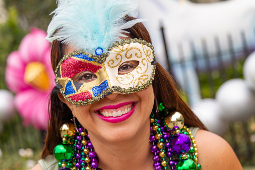 A young latin tourist female, wearing mask, costumes and necklaces celebrating Mardi Gras through the streets in New Orleans. This is the most important celebration for the city.
