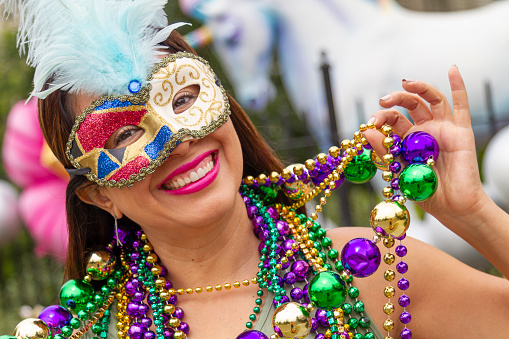 A young latin tourist female, wearing mask, costumes and necklaces celebrating Mardi Gras through the streets in New Orleans. This is the most important celebration for the city.