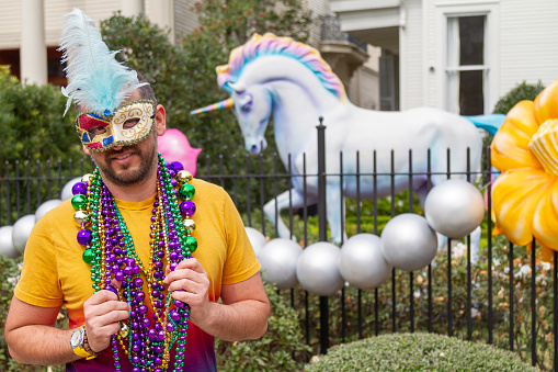 A young latin tourist male, wearing mask, costumes and necklaces celebrating Mardi Gras through the streets in New Orleans. This is the most important celebration for the city.