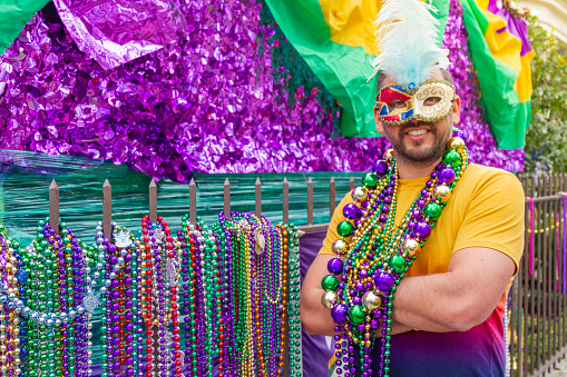 A young latin tourist male, wearing mask, costumes and necklaces celebrating Mardi Gras through the streets in New Orleans. This is the most important celebration for the city.