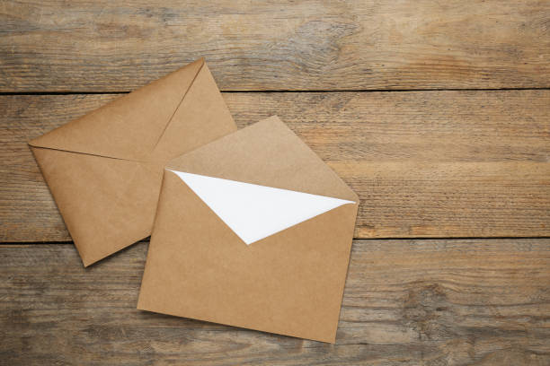 istock Envelopes with blank paper card on wooden table, flat lay. Space for text 1452873618