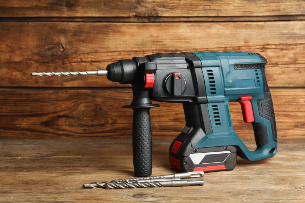 istock Modern electric power drill with bits on wooden table 1452873798