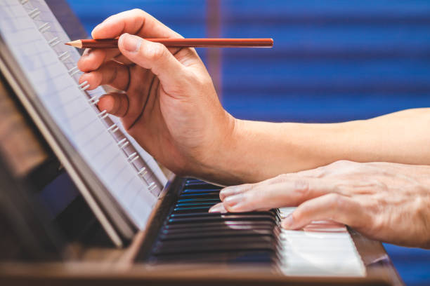 The Best Ways to Find Inspiration for Your Songwriting 10 close up male musician hand writing a hit song while playing acoustic piano songwriting