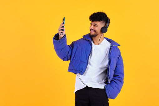 beautiful portrait of a young man taking a photo with an smartphone and using headphones