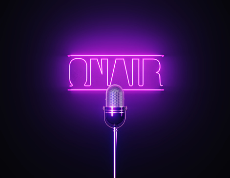 Purple neon light writes on air above a silver colored microphone over black background. Horizontal composition with copy space.