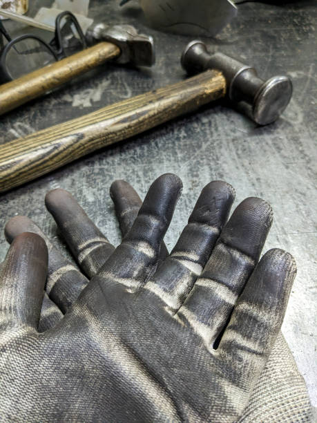 istock Black blacksmith work gloves against a sledgehammer background. Hard men's work as a blacksmith. 1452880185
