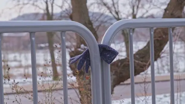 Lost Winter Warm Mitten Glove Hanging on Street Sidewalk Guard Rail