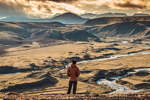 Rear view of traveler man standing on volcanic mountain and sunset sky in Icelandic Highlands on summer at Iceland