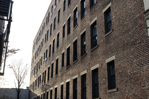 Perspective view of a featureless brick urban apartment building with rows of windows, horizontal aspect