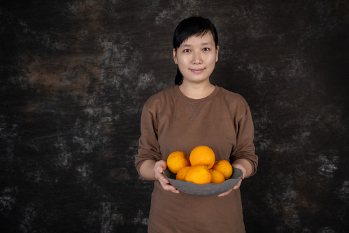 A housewife holds a plate of fresh orange
