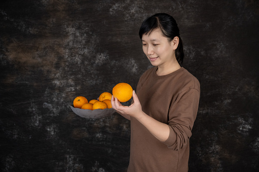 A housewife holds a plate of fresh orange