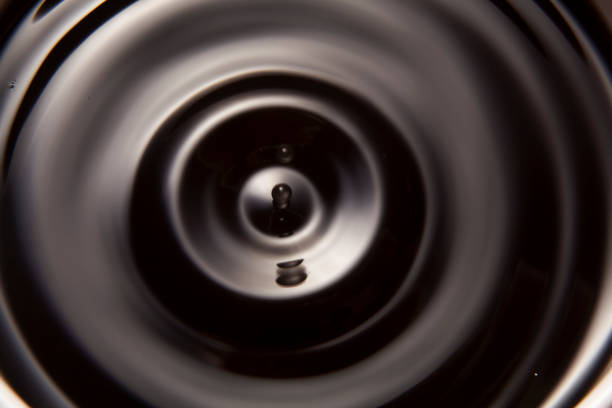 A drop of water falls into the black liquid and causes a wave