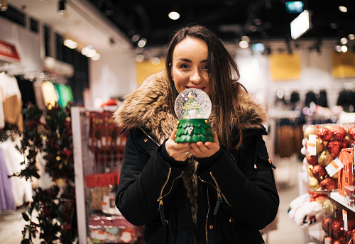 Young woman is shopping in the store. Christmas and New Year shopping gadgets. Having fun looking for the best presents. Bying nice decoration ornaments for better home interior decor.