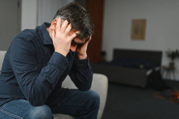 istock Middle age grey-haired man stressed sitting on sofa at home 1452892403