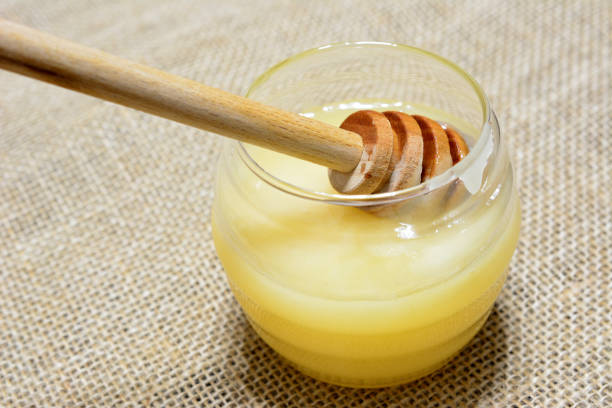 istock honey jar with honey stick isolated on burlap texture, macro 1452896608