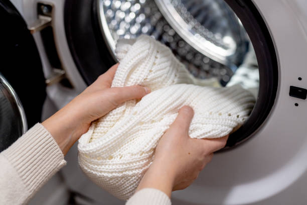 femme mettant des vêtements blancs dans le tambour d’une machine à laver, vue de face. laver les vêtements sales dans la laveuse - linge photos et images de collection