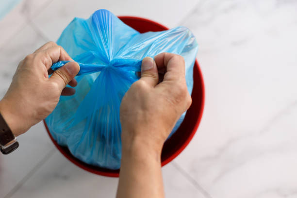 hände binden eine blaue plastiktüte, hochwinkelansicht - garbage bag garbage bag plastic stock-fotos und bilder