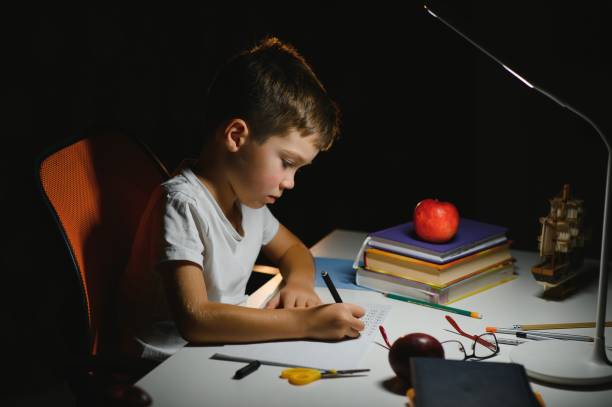 istock Boy learn lessons in the home setting at the table in the light of a table lamp. 1452900713