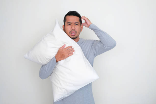 istock Adult Asian man holding a sleeping pillow with confused expression 1452903555