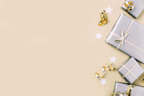 istock Light beige flat lay with gift boxes in silver paper package with golden ribbon 1452908306