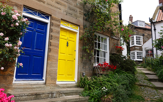 Robin Hood's Bay, UK - June 28, 2022: Blue and yellow coloured front doors in the village of Robin Hood's Bay, Yorkshire, UK.