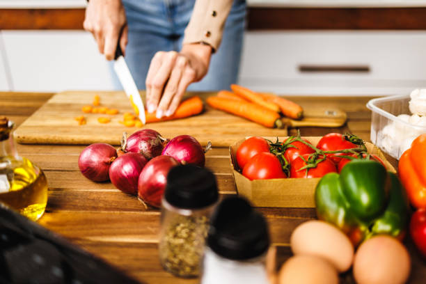 istock Young unrecognizable woman cutting vegetables for healthy meal 1452910929