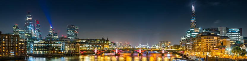 The glittering spires of the City skyscrapers and the futuristic towers of the South Bank overlooking the River Thames illuminated at night in the heart of London, the UK’s vibrant capital city.