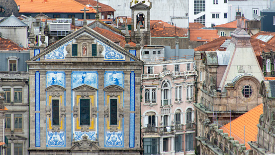 City panorama over the rooftops of Porto, Portugal with the colorful facade of the Church of Santo António dos Congregados.