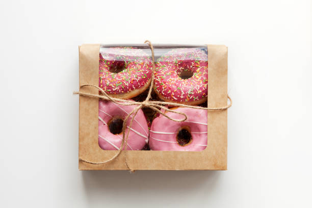 Pink donuts packed in box isolated on white background, natural light stock photo