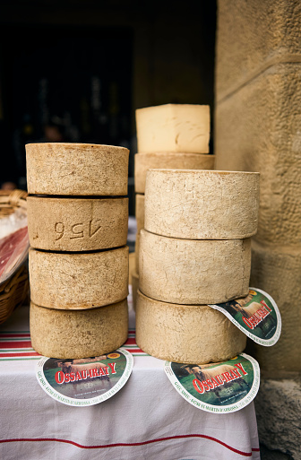 San Sebastian, Basque Country, Spain - December 21, 2022: A pile of Ossau-Iraty cheese wheels, a typical basque cheese, in a traditional market.