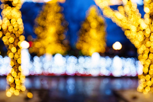 Out of Focus Holiday Lights Bokeh - Evergreen trees decorated with Christmas Tree lighting with out of focus bokeh balls. Blue and yellow predominant colors.