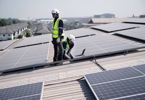 istock Caucasian and African American engineer man use electric screwdriver and computer notebook working with solar panel on roof factory 1452924257