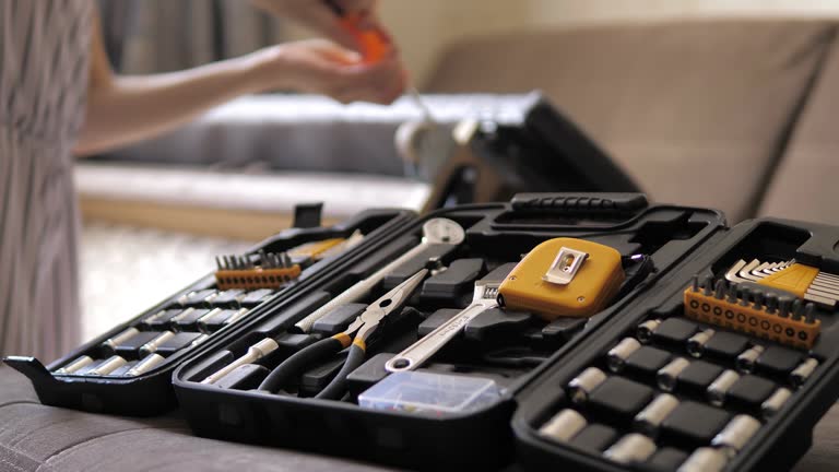 Closeup of young girls hands disassembles the sofa, unscrews the screw with a screwdriver. Heavy assembly of home furniture by yourself.Restoration of soft furniture.Stretching soft furniture at home