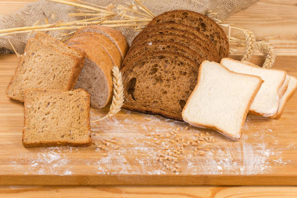 różne krojone chleby na desce do krojenia z uszami, ziarnem, mąką - brown bread zdjęcia i obrazy z banku zdjęć