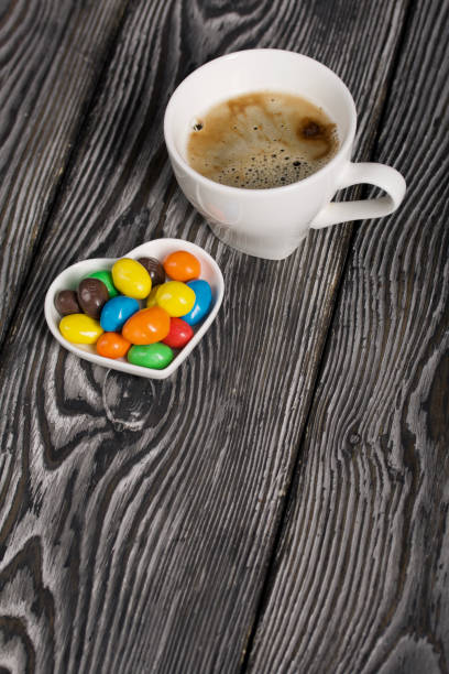 Time for a black coffee at home in the kitchen table with delicious cookies , cashews and dark chocolate .